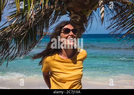 Primo piano di un woan seduto su una palma e ridendo con il mare sullo sfondo, a Zoni Beach a Culebra, Puerto Rico