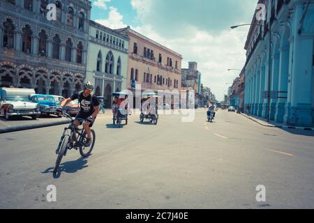 Havana / Cuba - 04.15.2015: Un biker che gira come due tipici taxi cubani in bicicletta, aka bicitaxi, sono in bicicletta per le strade di l'Avana, Cuba. Foto Stock