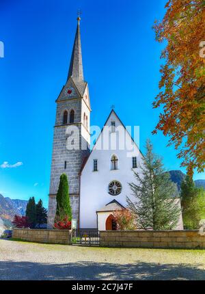 Montagne sopra il villaggio di Gosau con la Chiesa cattolica sotto la luce del sole. Località: villaggio turistico Gosau Salzkammergut regione, Valle di Gosau, alta Austria, Foto Stock