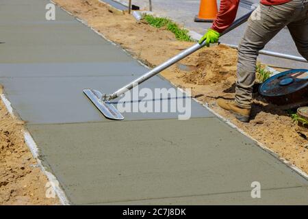 Costruzione muratore costruzione di un rivestimento di rasatore cemento un operaio galleggia un nuovo marciapiede di cemento Foto Stock