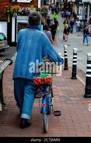 Una donna spinge UNA bicicletta attraverso High Street, Lewes, East Sussex, Regno Unito Foto Stock