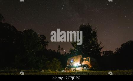 Campeggio in un campeggio circondato da alberi verdi sotto il cielo stellato Foto Stock