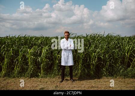 Lunghezza completa dell'agronomo tecnico caucasico maschile con computer tablet nel campo del mais che controlla la qualità e la crescita delle colture per l'agricoltura. Foto Stock