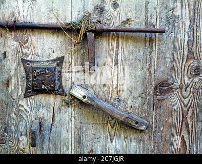 Dettaglio su una vecchia porta fienile con maniglia, chiavistello in ferro e serratura in Alto Adige Foto Stock