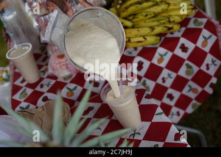 La persona versa un po' di frullato in una tazza di plastica Foto Stock