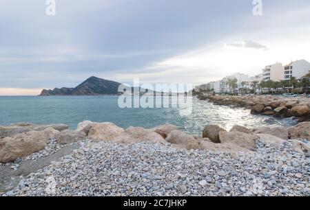 Tramonto lungo la passeggiata costiera di Altea con spiaggia di pietra con vista sulla montagna e l'oceano, Altea, Costa Blanca, Spagna Foto Stock