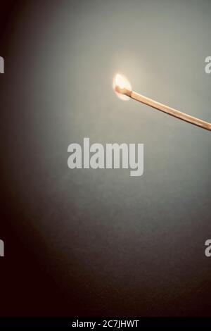 Immagine in primo piano verticale di un matchstick che brucia splendidamente in un camera oscura Foto Stock