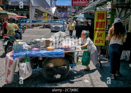 Donna anziana che lavora. Vendita di cibo di strada che spinge carrello a mano. Thailandia Sud-est asiatico Foto Stock