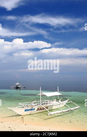 Outrigger tradizionale barca da pesca ormeggiata sulla spiaggia sulla costa orientale dell'isola di Malapascua, Cebu, Visayas Centrale, Filippine Foto Stock