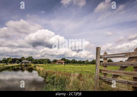 Bellissimo scatto di un campo erboso con edifici nel distanza sotto un cielo nuvoloso Foto Stock