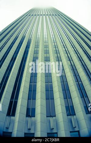 Edificio Skyscaper con linee architettoniche verticali che torreggiano dal cielo, dalla vista a livello della strada allo sciopero del sole sulla sommità dell'edificio, in tonalità verde. Foto Stock