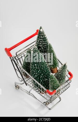 Alberi di Natale in miniatura nel carrello, dall'alto, sfondo bianco, immagine icona, shopping di Natale, Foto Stock