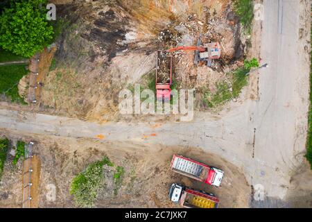 vista aerea, escavatore arancione con camion in cantiere. vista dall'alto riqualificazione urbana Foto Stock
