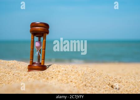 Il tempo di uno spettacolo in clessidra scorre su uno sfondo di sabbia e sabbia. Foto Stock