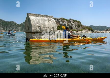 Un kayak passa accanto a una delle tombe licane sommerse nell'antica città di Simena. Il sito è oggi il moderno villaggio di pescatori di Kalekoy in Turchia Foto Stock