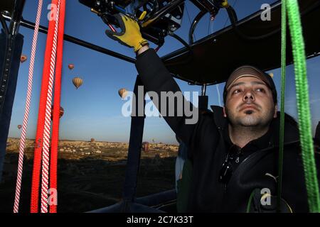 Un pilota di mongolfiera controlla il traffico aereo su Goreme durante un volo mattutino nella regione della Cappadocia in Turchia. Foto Stock