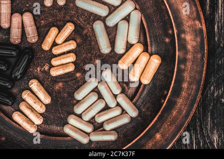 Pillole multivitaminiche su una piastra di argilla, su una tavola di legno vintage Foto Stock