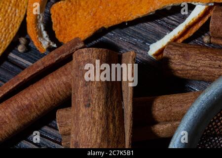 Cannella, croste d'arancia, spezie e setaccio di metallo su un tavolo di legno Foto Stock