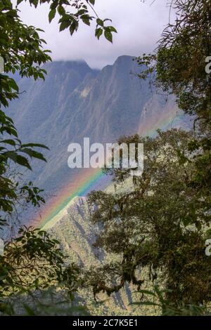 Arcobaleno visto attraverso la vegetazione giù sopra la valle del fiume Urubamba, sul sentiero Inca a Machu Picchu, Perù Foto Stock