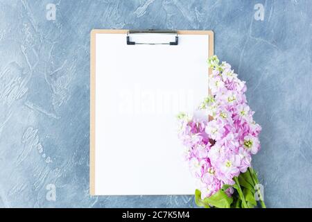 Appunti con carta bianca bianca e fiori su sfondo bianco. Concept spazio di lavoro femminile Mockup Vista dall'alto Flat Lay. Spazio per il testo. Foto Stock