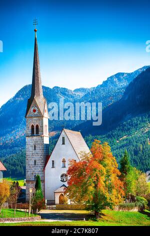 Montagne sopra il villaggio di Gosau con la Chiesa cattolica sotto la luce del sole. Località: villaggio turistico Gosau Salzkammergut regione, Valle di Gosau, alta Austria, Foto Stock