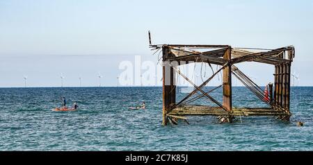 Brighton UK 18 luglio 2020 - i paddle boarders passano dal molo ovest a Brighton questa mattina in una bella giornata di sole sulla costa meridionale con temperature attese per raggiungere gli alti 20 in alcune parti della Gran Bretagna : Credit Simon Dack / Alamy Live News Foto Stock