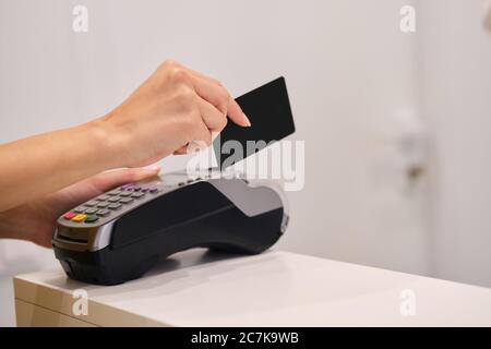 Primo piano mani donna che pagano con carta di credito in negozio moderno Foto Stock