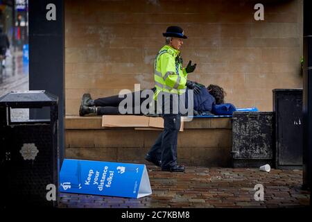 Manchester Market Street un ufficiale PCSO risveglia un uomo senza casa Foto Stock