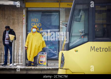 I passeggeri della stazione del tram Metrolink dei Manchester Piccadilly Gardens indossano maschere che aspettano il loro tram Foto Stock