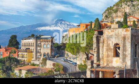 Vista panoramica aerea del vulcano Etna e della città di Taormina. Tetti di molte abitazioni. Fumo sul vulcano Etna innevato. Taormina, Sicilia, Italia. Foto Stock