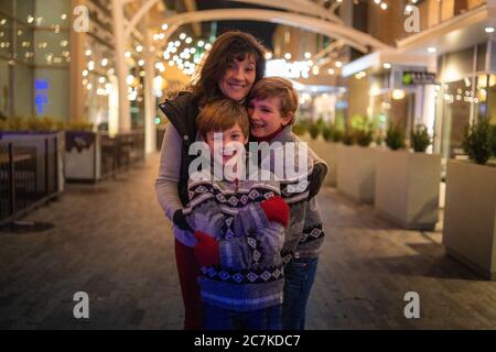 Madre con i suoi due figli in giacche identiche che si posano all'esterno - concetto di tempo familiare Foto Stock