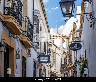 Ristoranti e negozi fiaccano la stretta e tortuosa Calle Cespedes di Cordoba mentre si snoda dalla storica moschea-cattedrale. Foto Stock