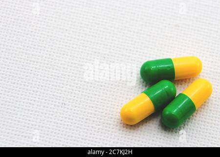 Shot di closeup ad angolo alto di capsule gialle e verdi su una superficie bianca Foto Stock