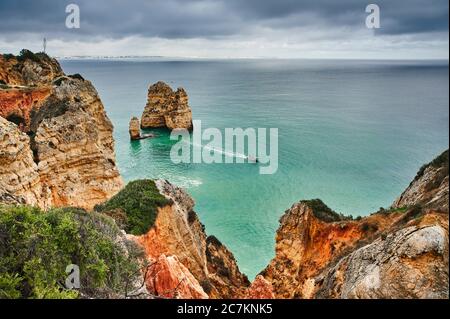 Europa, Portogallo, Algarve, Litoral, Barlavento, Felsalgarve, Distretto di Faro, Lagos, la costa di Ponta da Piedade, scogliera di roccia offshore e piccolo motoscafo Foto Stock