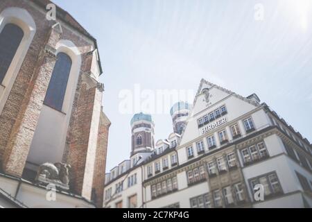 Le torri a cipolla della Frauenkirche a Monaco, in primo piano una ben nota Kaufhaus di Monaco. Foto Stock