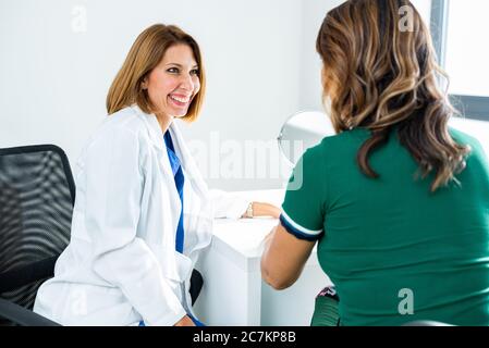 Consultazione in clinica cosmetologica. Donna medico che parla con paziente Foto Stock