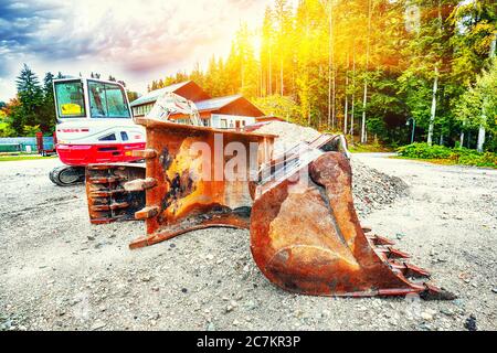 Escavatore in estate giorno in foresta sullo sfondo di alberi. Benne variabili sulla parte anteriore Foto Stock