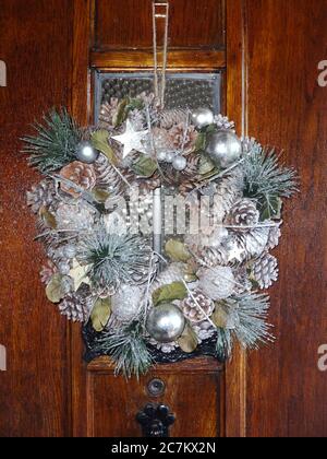 Corona di Natale appesa su una porta di legno durante il periodo festivo che celebra la presepe di Gesù Cristo foto d'azione Foto Stock