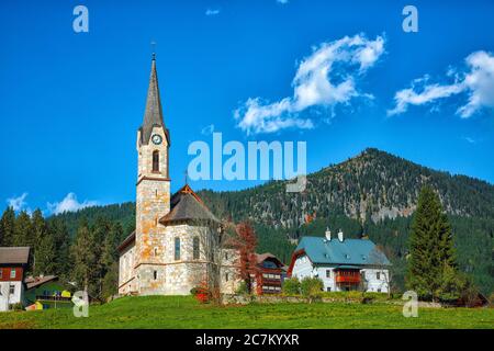 Montagne sopra il villaggio di Gosau con la Chiesa cattolica sotto la luce del sole. Località: villaggio turistico Gosau Salzkammergut regione, Valle di Gosau, alta Austria, Foto Stock