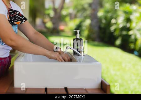 Donna che le lava le mani con acqua all'aperto. Foto Stock