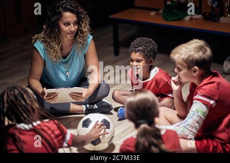 Allenatore donna che spiega il piano di gioco ai giocatori di calcio. Foto Stock