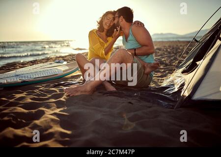 giovane coppia caucasica seduta insieme in spiaggia con gambe intrecciate, coccolate, stuzzicadenti, godendosi. spazio copia Foto Stock