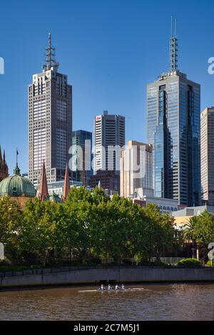 Una barca a remi con quattro persone sul fiume Yarra con alti edifici sullo sfondo, del centro della città di Melbourne, Victoria, Australia Foto Stock