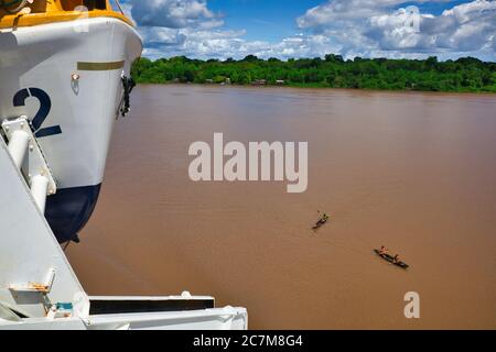 Vista da vicino a una barca di salvataggio del fiume Amazzonia con due canoe in legno aperto sul fiume nelle vicinanze e la foresta pluviale oltre, nello stato di Para, Brasile Foto Stock