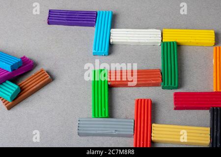 Plastilina multicolore su carta grigia, concetto di puzzle Foto Stock