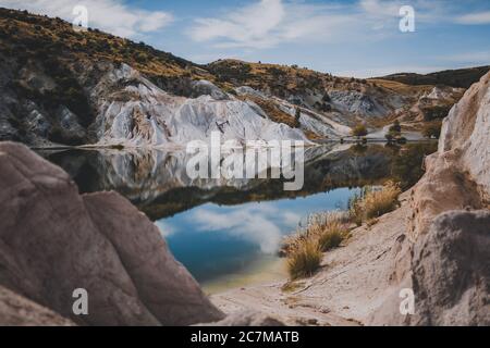 Bellissimo scatto di Blue Lake circondato da colline sotto un Cielo blu in Nuova Zelanda Foto Stock