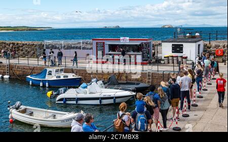North Berwick, East Lothian, Scozia, Regno Unito, 18 luglio 2020. Regno Unito Meteo: Sole estivo in una città molto trafficata di mare che è tornato alla normalità, anche se con misure di allontanamento sociale in atto. Il popolare Lobster Shack ha una lunga coda socialmente distanziata intorno al porto Foto Stock