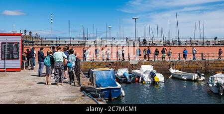 North Berwick, East Lothian, Scozia, Regno Unito, 18 luglio 2020. Regno Unito Meteo: Sole estivo in una città molto trafficata di mare che è tornato alla normalità, anche se con misure di allontanamento sociale in atto. Il popolare Lobster Shack ha una lunga coda socialmente distanziata intorno al porto Foto Stock