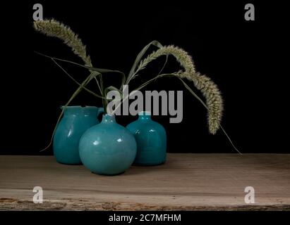 ancora vita con tre vasi blu, orecchie di mais su uno sfondo scuro con luce dal lato destro Foto Stock