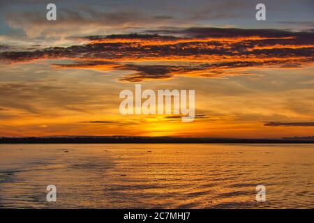 Alba sul fiume Amazon alle 6:00 con il suggestivo rosso arancio e giallo alba cielo mattina e la scia della nave in primo piano. Foto Stock